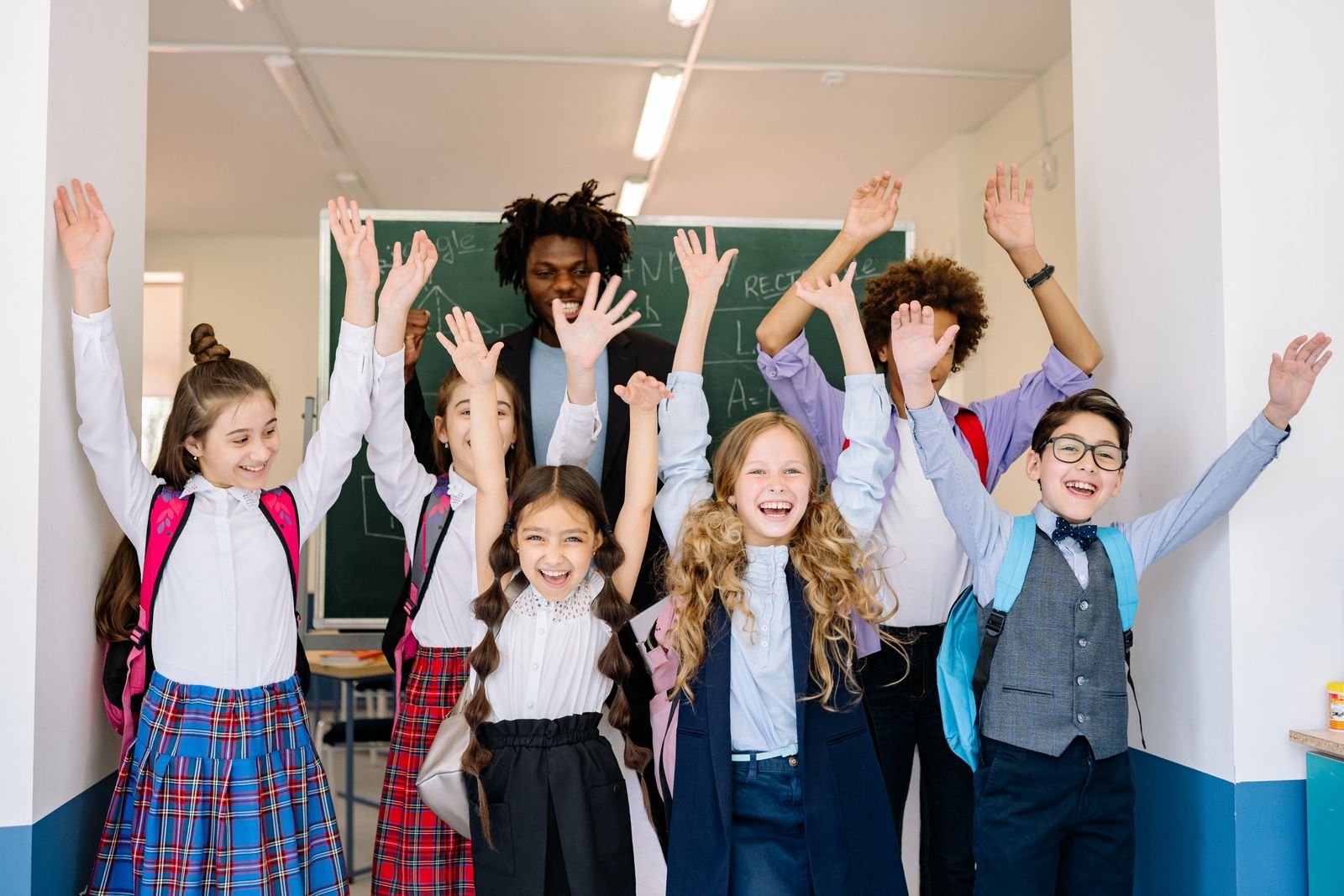 Illustrative photograph of enthusiastic pupils raising their hands in a classroom